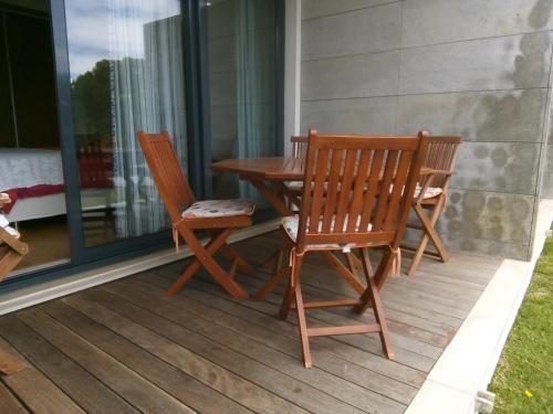 two wooden chairs and a table on a porch at Casa das Dunas Soltroia in Troia