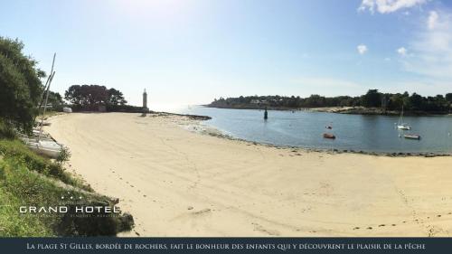 a sandy beach with boats in the water at Grand Hôtel Bénodet Abbatiale Riviera Bretonne in Bénodet