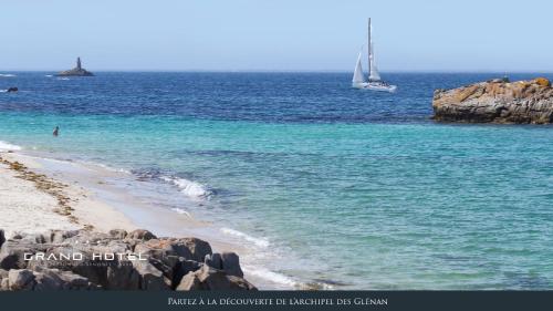 a sail boat in the ocean with a beach at Grand Hôtel Bénodet Abbatiale Riviera Bretonne in Bénodet