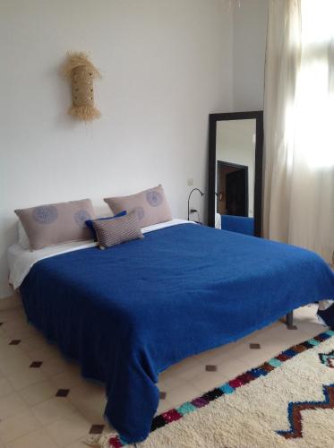 a bedroom with a blue blanket on a bed at La Maison des Ailleurs in Essaouira