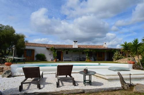 a house with a pool and two chairs and a table at Sa Rezzetta in Golfo Aranci