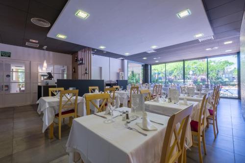 a dining room with white tables and yellow chairs at Hotel California Palace in Salou