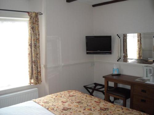 a bedroom with a bed and a desk and a television at Townstal Farmhouse in Dartmouth