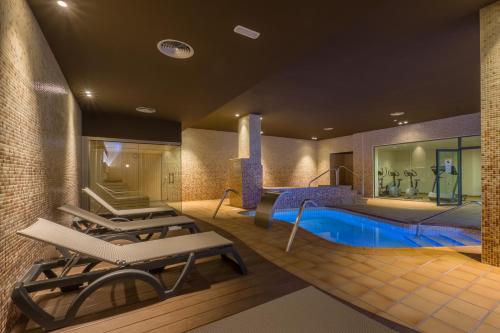 a room with a pool and lounge chairs and a swimming pool at Hotel California Palace in Salou
