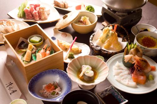 una mesa con muchos platos de comida. en Oyado Kiyomizuya, en Noboribetsu