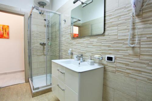łazienka z umywalką i prysznicem z lustrem w obiekcie Central Apartments w mieście Crotone