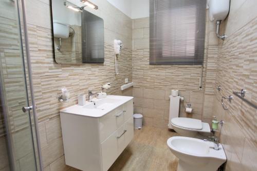 a bathroom with a sink and a toilet and a mirror at Central Apartments in Crotone