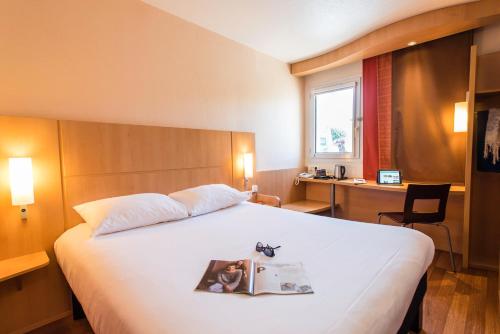 a hotel room with a bed with a magazine on it at ibis Château-Thierry in Essômes-sur-Marne