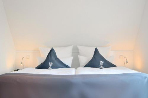 een groot bed met blauwe en witte kussens erop bij Rackmers Hof - Suiten Hotel garni mit Sauna in Oevenum