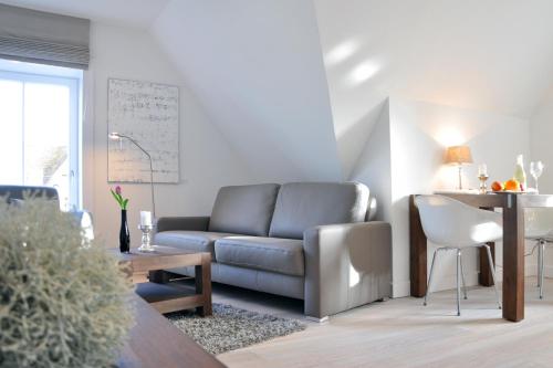 a living room with a couch and a table at Rackmers Hof - Suiten Hotel garni mit Sauna in Oevenum