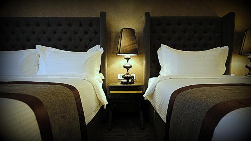 a hotel room with two beds and a lamp at 1969 Business Suites Bandar Botani, Ipoh in Ipoh