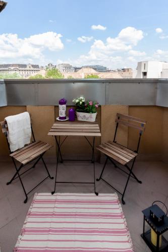 a balcony with two chairs and a table with flowers at Grand Budapest Penthouse in Budapest