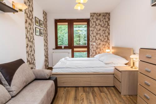 um quarto com uma cama, um sofá e uma janela em udanypobyt Apartamenty Pastelowe em Zakopane