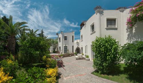 a large white building with a patio and trees at Torbahan Hotel in Torba