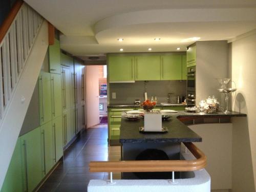 une cuisine avec des placards verts et une table. dans l'établissement Executive suite in Zug Old Town Triplex, à Zoug