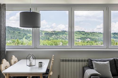 een tafel en stoelen in een kamer met ramen bij udanypobyt Smrekova Apartament in Zakopane