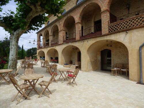an outdoor patio with tables and chairs and a building at Mas d'Asvin & Spa in Saint-Christol-lès-Alès
