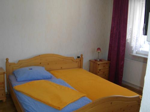 a bedroom with a wooden bed with a yellow blanket at Gasthof Zum Stausee in Engelskirchen