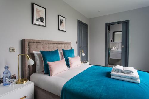 a bedroom with a blue bed with two towels on it at Farnborough Boutique by Viridian Apartments in Farnborough