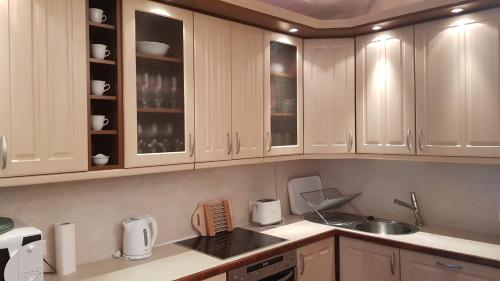 a kitchen with white cabinets and a sink at Mimi Apartman in Balatonalmádi