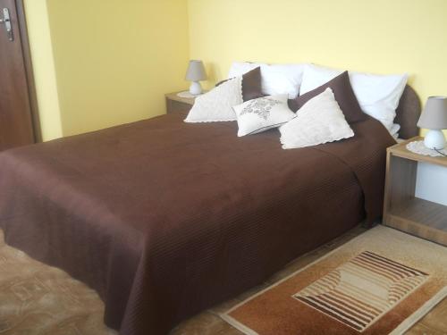 sypialnia z dużym brązowym łóżkiem z poduszkami w obiekcie U Derca w mieście Gnieżdżewo