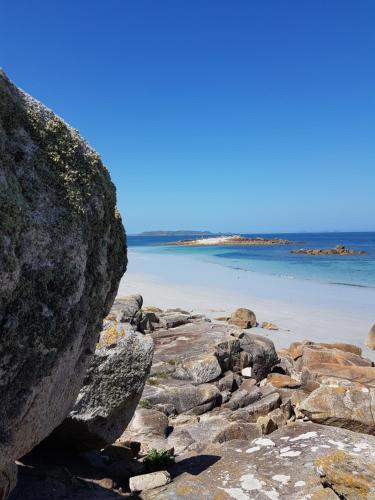 a large boulder on a beach with the ocean in the background at Résidence CoatArmor in Tonquédec