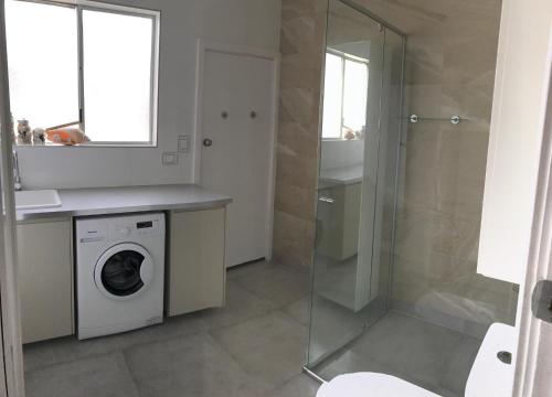 a bathroom with a washing machine and a shower at Salty Shack Lancelin in Lancelin