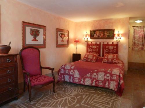 a bedroom with a red bed and a chair at Mas de la Chapelle in Arles