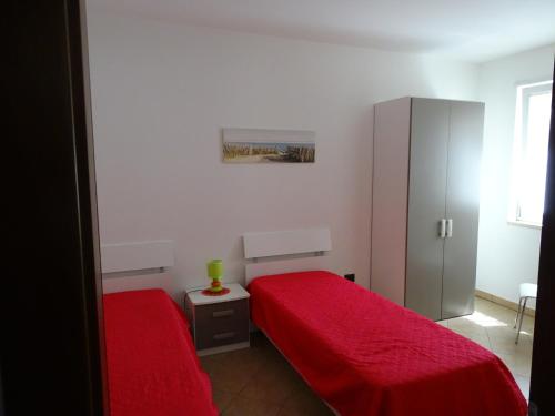 ガリポリにあるhouse gallipoliのベッドルーム1室(赤いベッド2台、キャビネット付)