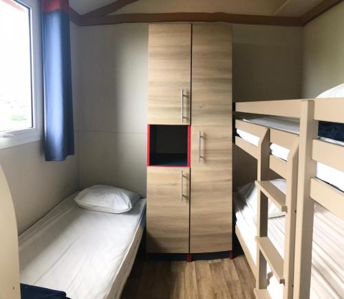 a small bedroom with a bunk bed and a cabinet at Camping Trinité in Bonifacio