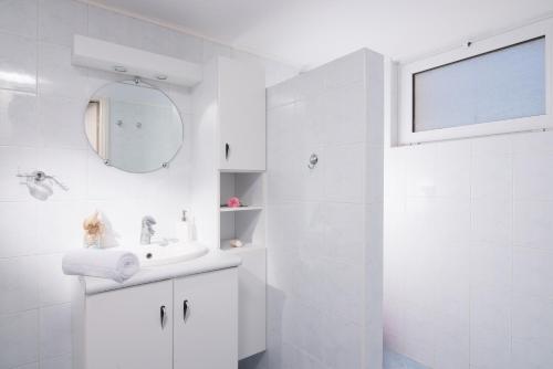 een witte badkamer met een wastafel en een spiegel bij Casa Di Mario in Kokkíni Khánion