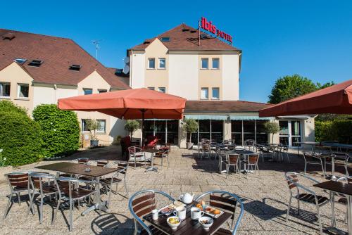 a patio with tables and chairs in front of a hotel at Ibis Château-Thierry in Essômes-sur-Marne