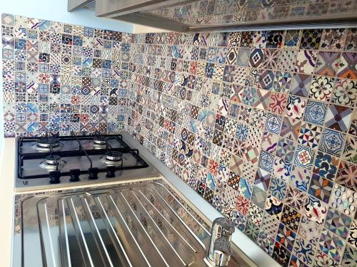 a kitchen with mosaic tiles on the wall at Mazzitelli Apartment in Capo Vaticano