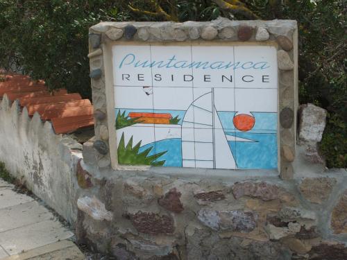 ein Schild an einer Steinmauer mit einem Segelboot darauf in der Unterkunft Una Finestra sul Mare in Calasetta