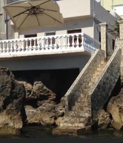 a bridge with a balcony and an umbrella over the water at Villa Rena In Front of the Sea in Arkoudi