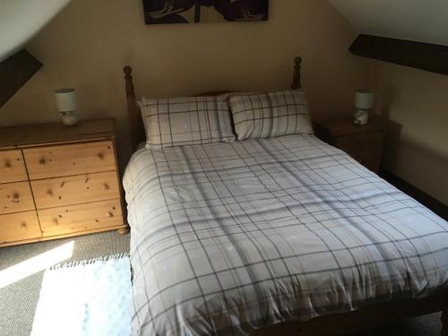 - un lit avec une couverture tressée et une commode en bois dans l'établissement Stable Cottage, à Scarborough