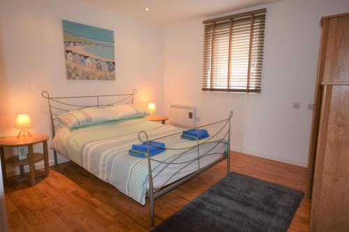a bedroom with a bed and two lamps and a window at Coastal Apartments - Wales in Swansea