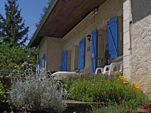 a house with blue windows and chairs and flowers at le lansquenet in Rorbach-lès-Dieuze