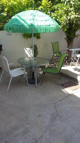 a table and two chairs and a green umbrella at Marina's Rooms in Larnaka