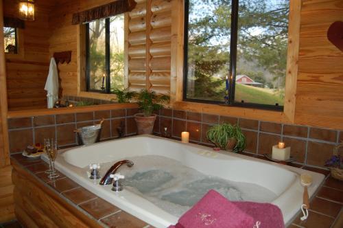 een bad in een houten badkamer met kaarsen bij Mountain Springs Cabins in Candler