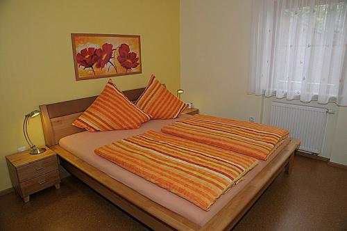 プラインフェルトにあるHaus Traumblickのベッドルーム1室(オレンジとオレンジの枕が付いたベッド1台付)