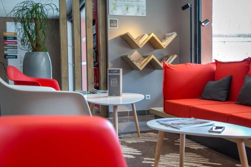 a waiting room with red chairs and tables at ibis Cannes Mandelieu in Mandelieu-la-Napoule