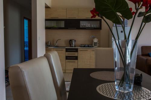 un jarrón con flores sobre una mesa en una cocina en Aqua Line Apartmanház en Hajdúszoboszló