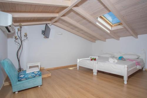 a attic room with two beds and a chair at Alexandros Stone House in Nydri
