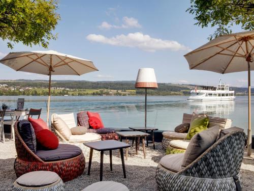 a group of chairs and tables with a boat in the water at Hotel-Restaurant-Schifflände in Birrwil