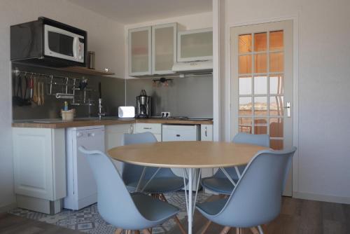 uma cozinha com uma mesa de madeira e cadeiras azuis em La Timonerie - La Caraque 35, vue mer et dunes classé 2 étoiles em Fort-Mahon-Plage