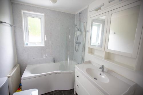 a white bathroom with a tub and a sink at Kelpies Cottage in Newton Stewart