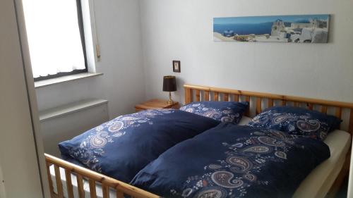 a bedroom with a bed with blue pillows and a window at Niedersfeld Polzweg in Winterberg