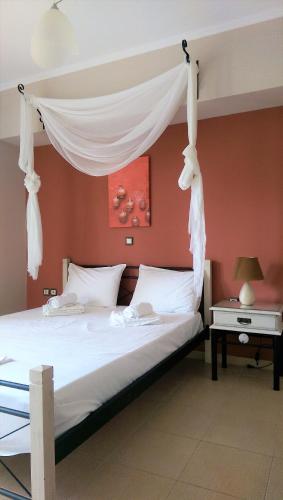 a bedroom with a white canopy bed with a table at Maria's Rose Garden in Lefkada