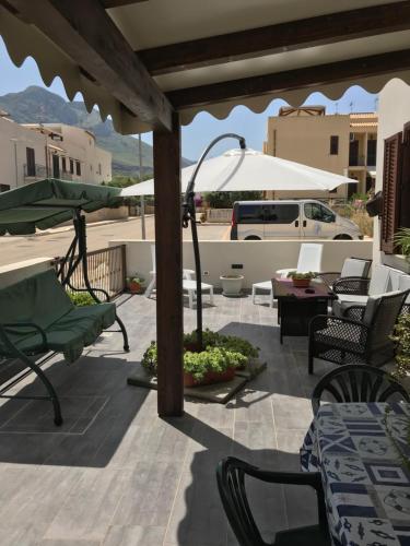 a patio with chairs and tables and an umbrella at Casa Rosita in San Vito lo Capo